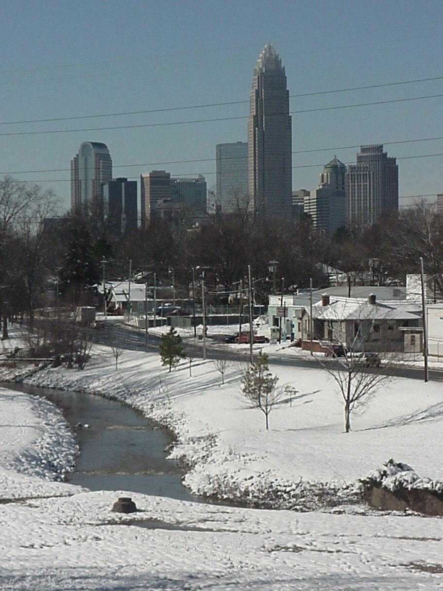 panoramic view of city and skyline after snow storm, creek runs along in the foregound