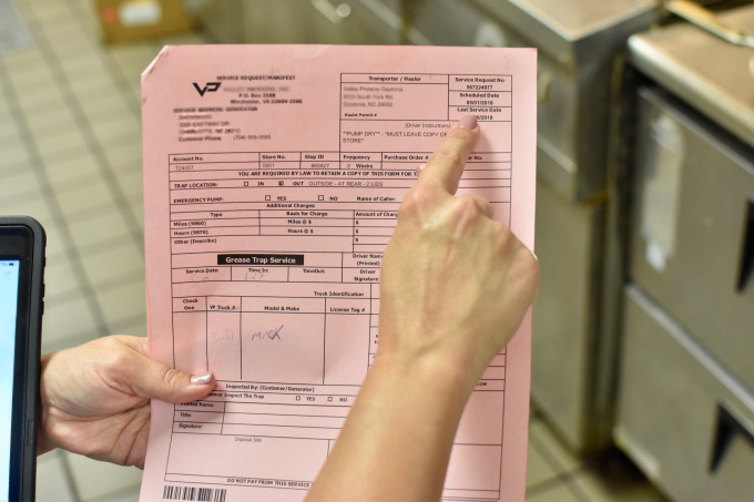 finger points at a cell on a pink piece of paper