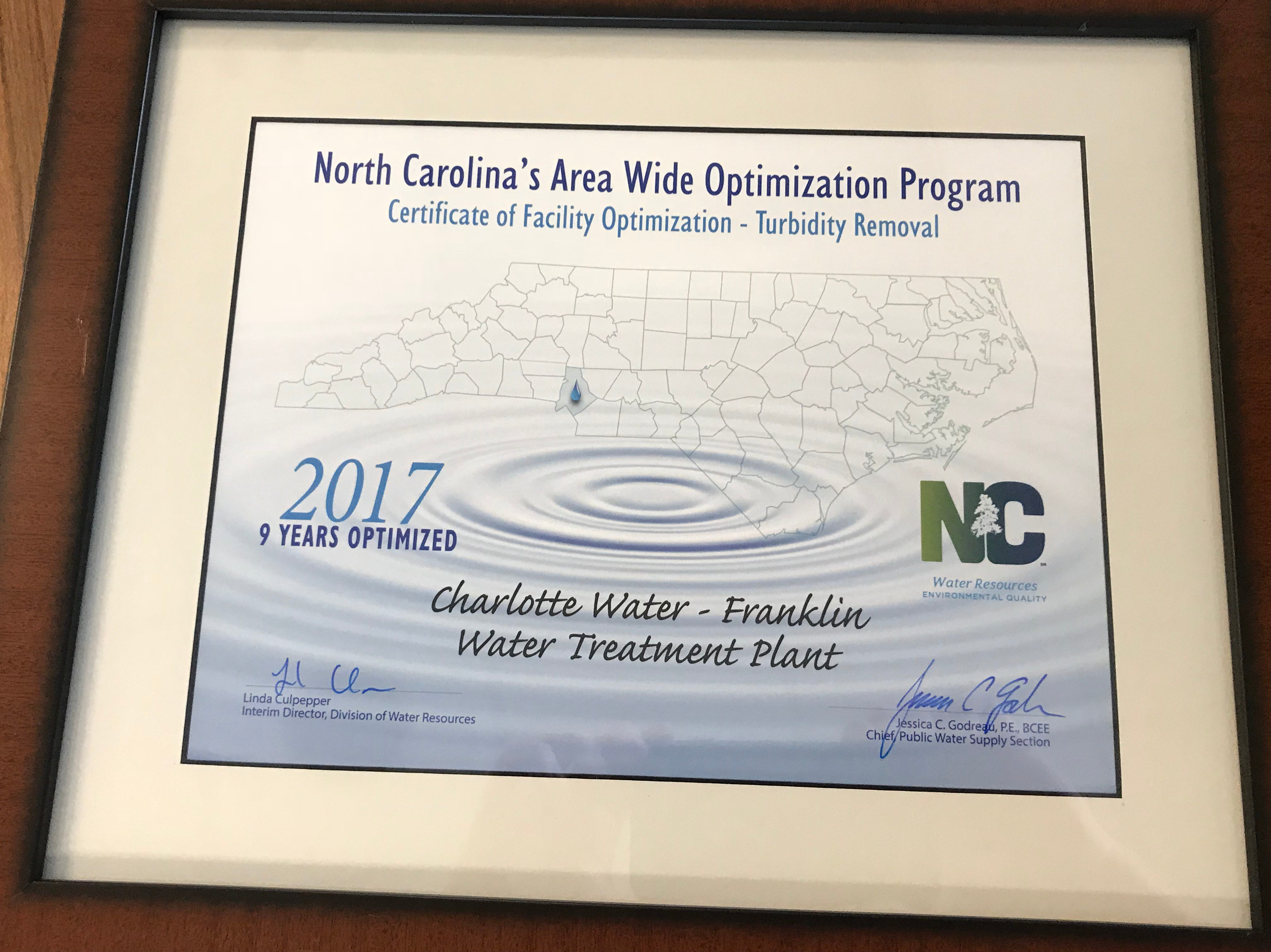 wood framed white and tan award certificate in black and blue font for Charlotte Water - Vest Water Treatment Plant on behalf of the North Carolina Area Wide Optimization Program Certification of Facility Optimization - Turbidity Removal, 2017 ten years optimized