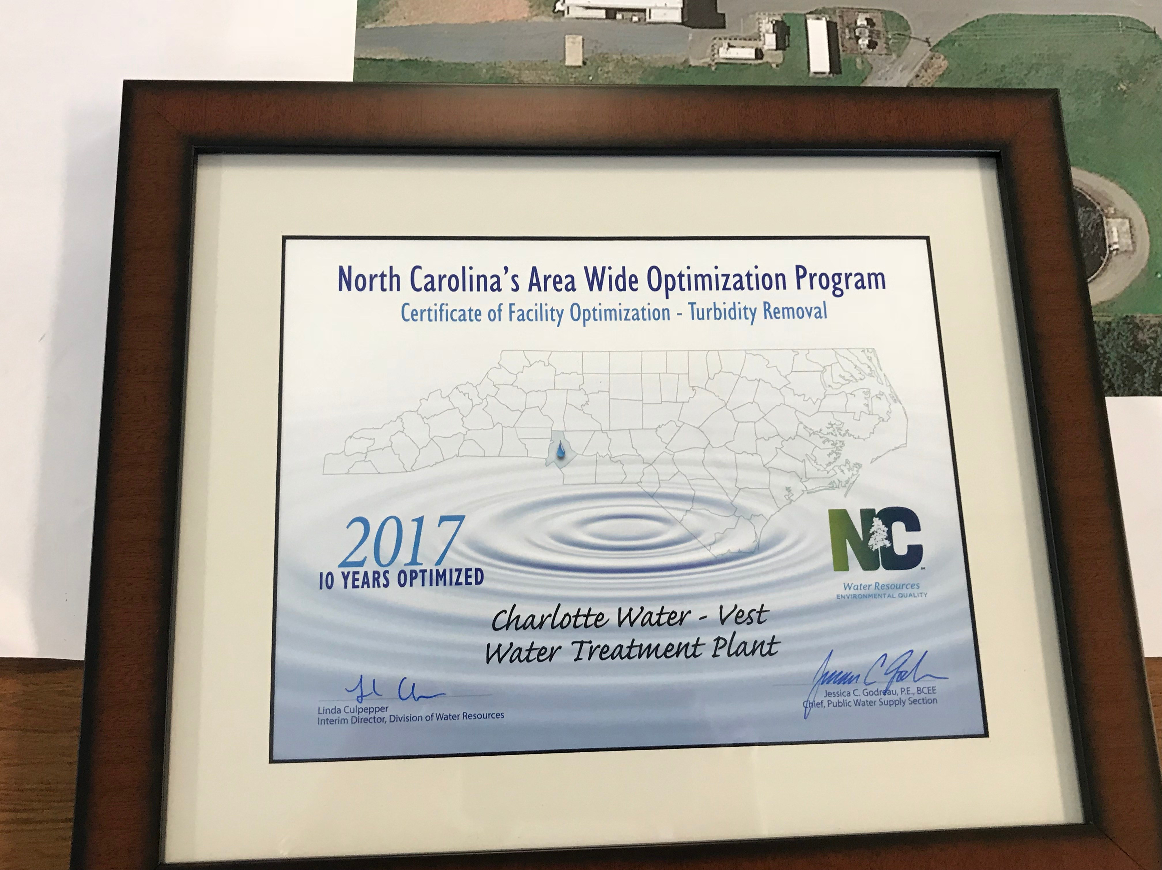 wood framed white and tan award certificate in black and blue font for Charlotte Water - Vest Water Treatment Plant on behalf of the North Carolina Area Wide Optimization Program Certification of Facility Optimization - Turbidity Removal, 2017 ten years optimized