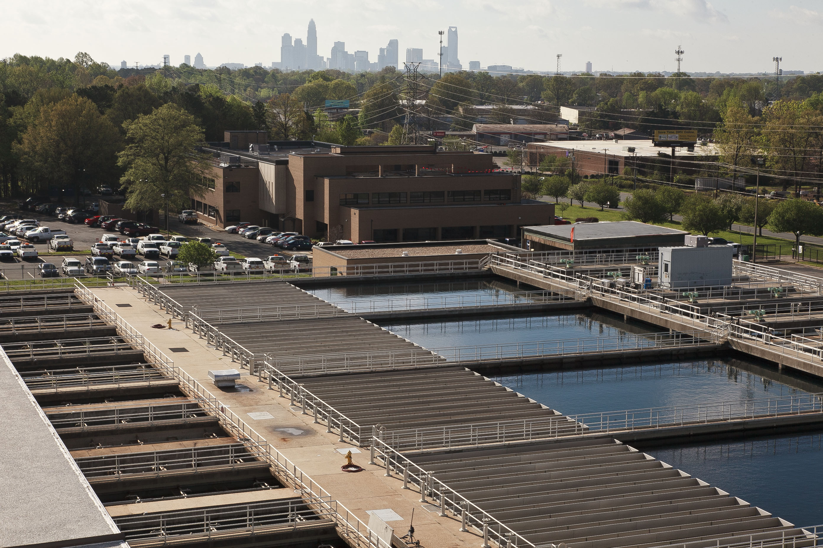 panoramic view of water treatment facility building and water treatment ponds and filter structures and a view of the city skyline and it's skyscrapers in the distance