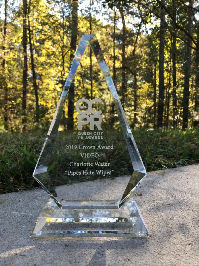 glass trophy sits on a concrete balcony wall with a forest scene behind it