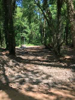 rock and gravel lined diversion culvert installed along a tree lined rural road
