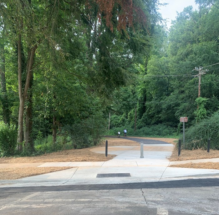 newly installed white concrete, tree-lined bike and walking path trailhead