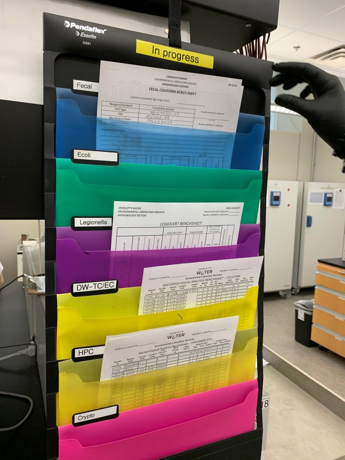 black plastic rack holds 5 colorful folders holding white lab test documentation papers