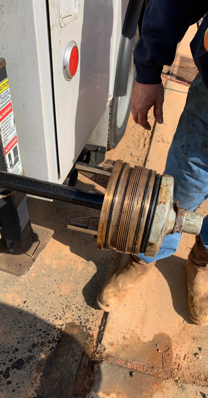 close up view of a cylindrical, copper cufflink styled part attached to a long pole as it awaits removal from the back of a utility truck