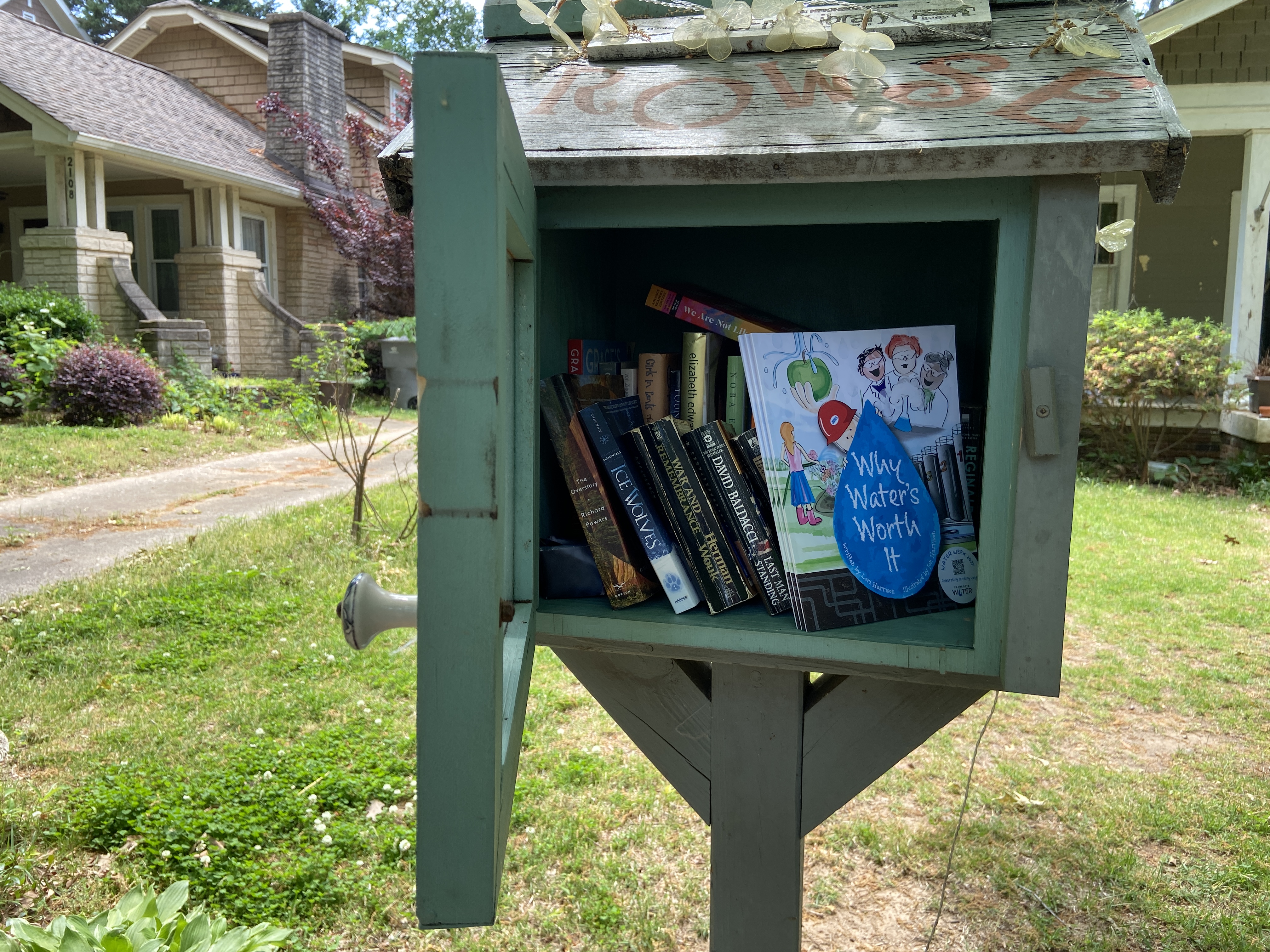 green curbside lending library box in a residential neighborhood featuring children's book Why Water's Worth It