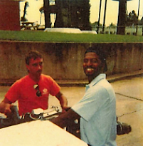2 employees sit a a picnic table one in orange t-shirt and the other in light blue dress shirt