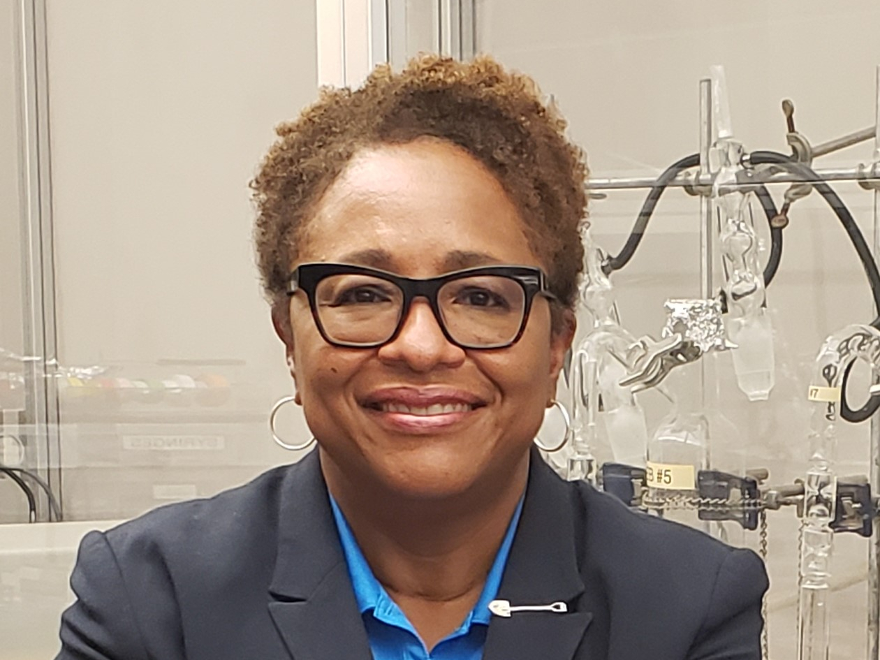 portrait of utility supervisor in a blue blouse and navy blue blazer with a shovel-shaped pin