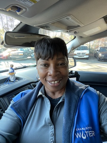 Selfie of utility staff member sitting in SUV wearing blue vest with Charlotte Water logo