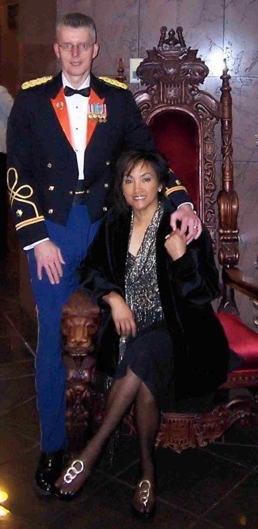 utility employee in full dress regalia from their days of service, poses with a woman seated on a wooden throne