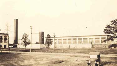 black and white photo of what an early water utility one-story plant facility looked like with two silo-like water towers