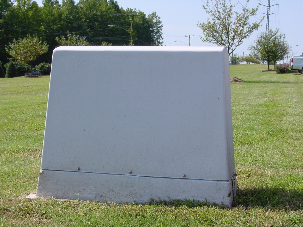 sitting on a grassy lawn is a large, white pvc casement cover for utility backflow prevention device
