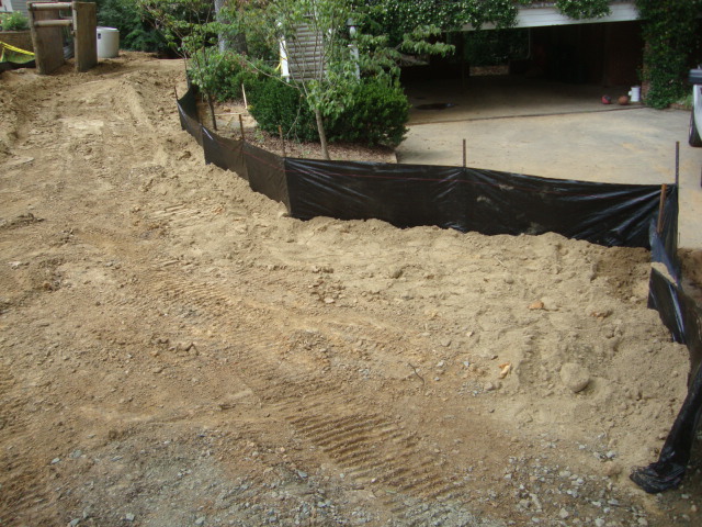 Recently turned earth pathway next to a black construction screen