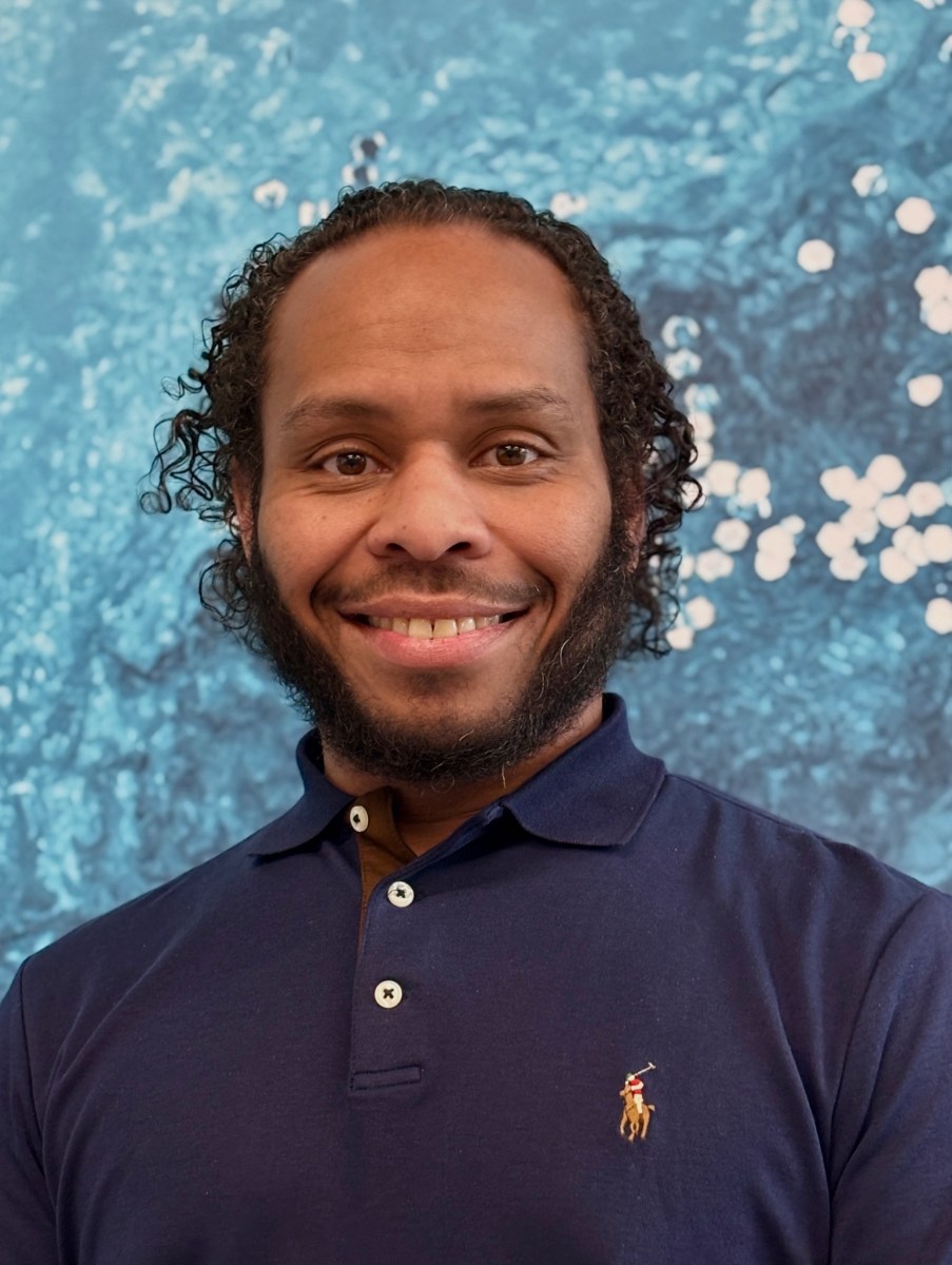Prole photo of utility apprentice with wavy dark hair, full beard and thin mustache wearing a navy blue polo shirt
