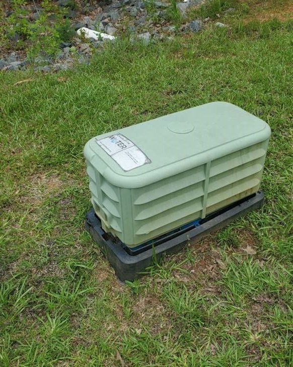 Light green rectangular, metal, vented box with on a black stand is installed on a green lawn. A Charlotte Water logo on a sticker appears on its roof.