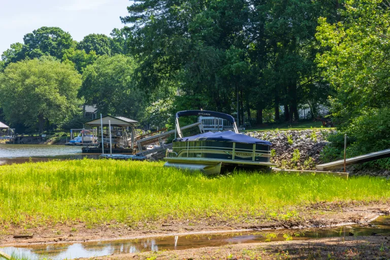 blue boat aground in grassy mud due to receding lake waters caused by drought
